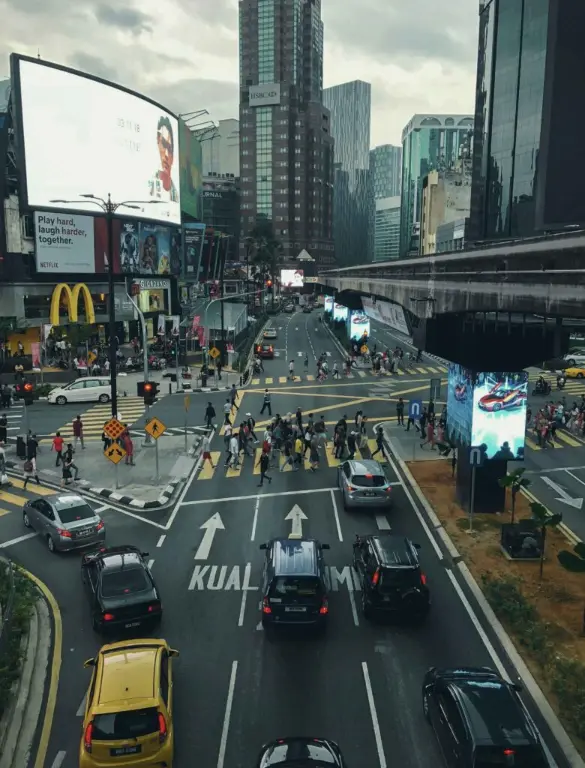 Scene of bukit bintang traffic showing cars, crowds crossing the sidewalk and people waiting for e-hailing services to arrive.