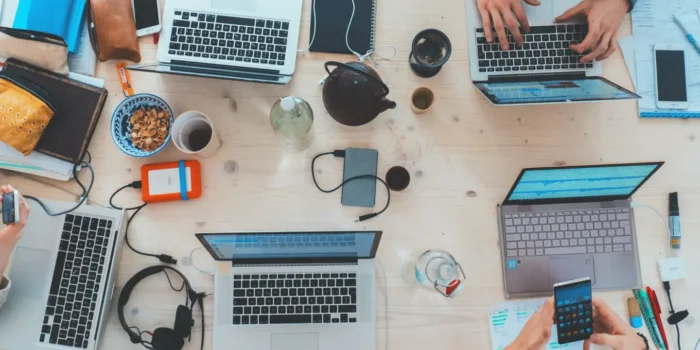An overhead shot of a shared workstation with people working on laptops signifying in-demand software engineer jobs.